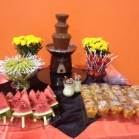 Mesa de frutas com cascata de chocolate.