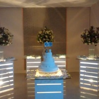 Mesa de bolo e doces em caixas de madeiras brancas com iluminao interna e tampos em vidro.