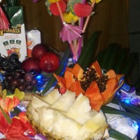 Mesa decorada com esculturas em frutas e e luzes.