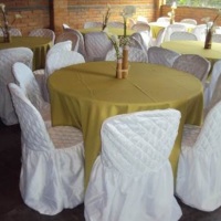 mesas redondas com toalhas e cadeiras com capas para locação.